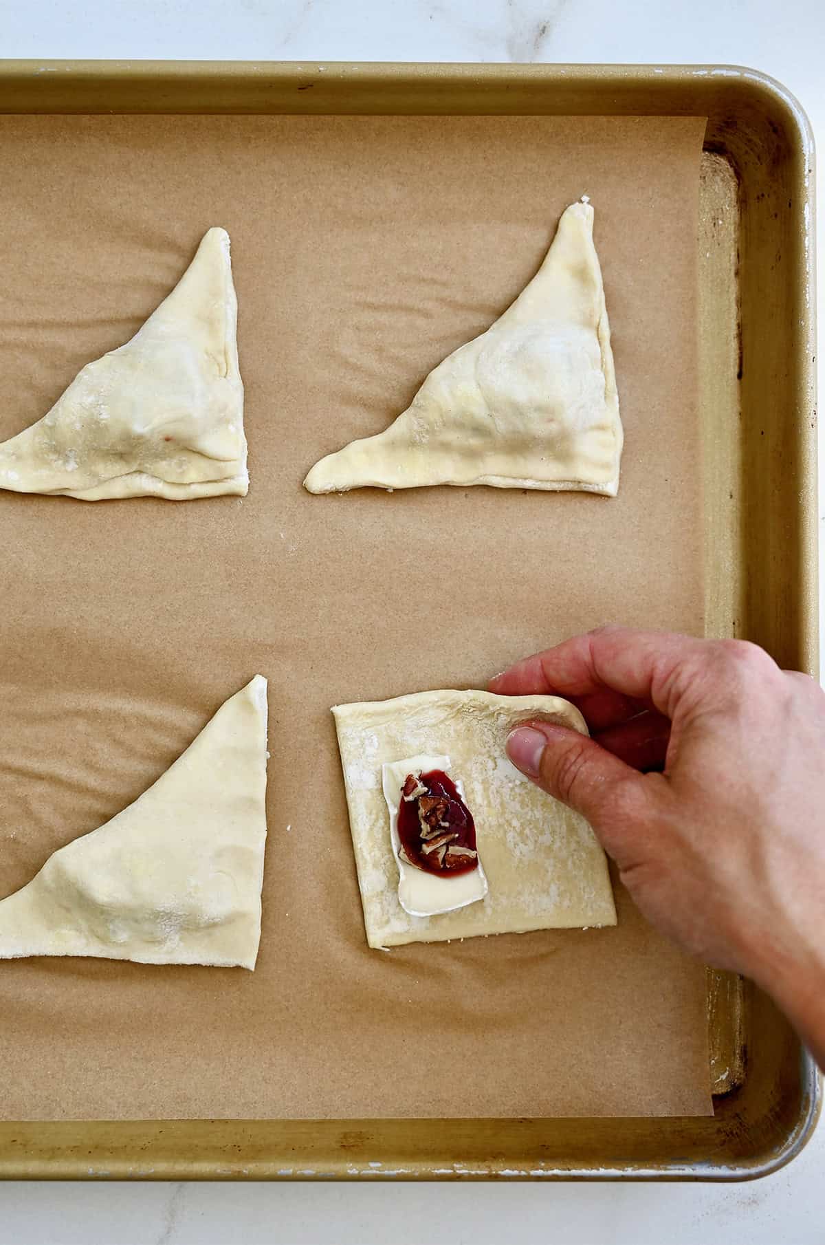 Puff pastry bites with jam and toasted nuts before going into the oven to bake.