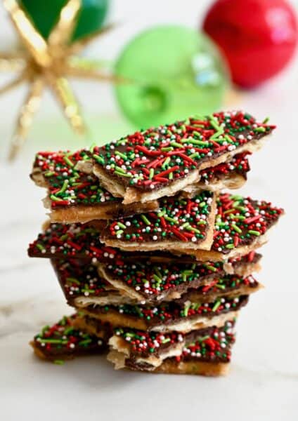 A tall stack of Christmas Crack in front of holiday ornaments.