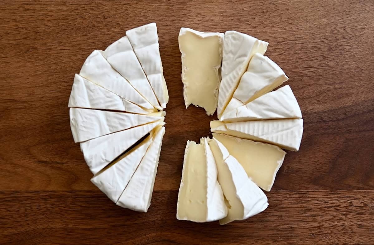 A brie wheel sliced into small wedges.