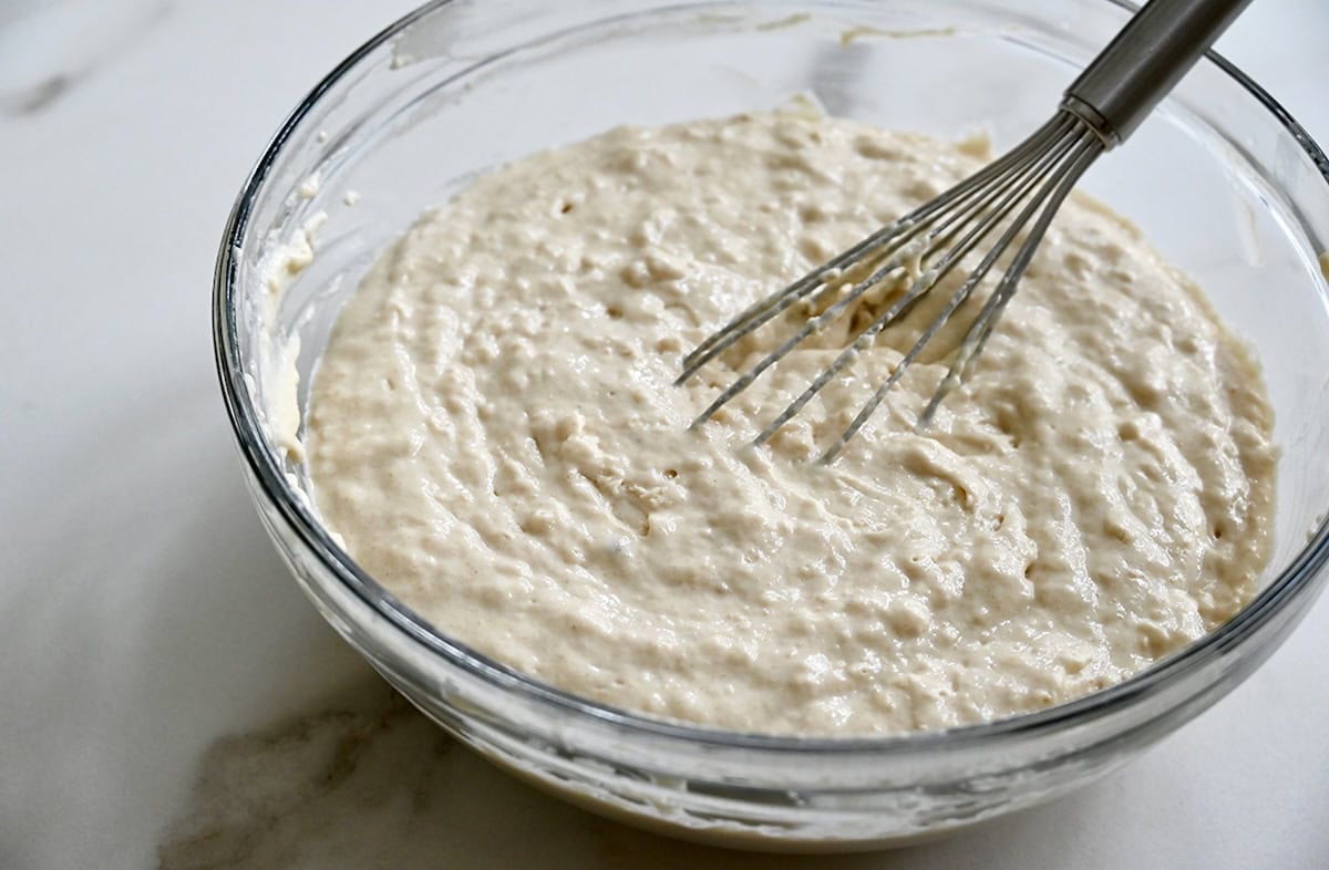 Lumpy sheet pan pancake batter in a glass bowl with a whisk.