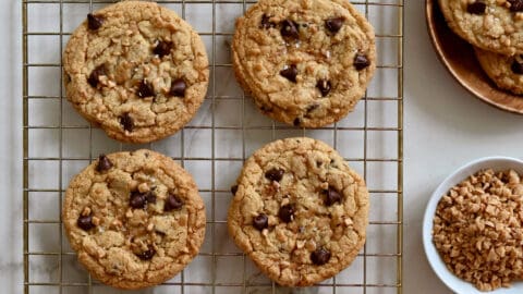 Toffee chocolate chip cookies garnished with large-flake sea salt cooling on a wire baking rack.