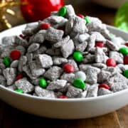 A white serving bowl containing muddy buddies with red, white and green M&Ms.