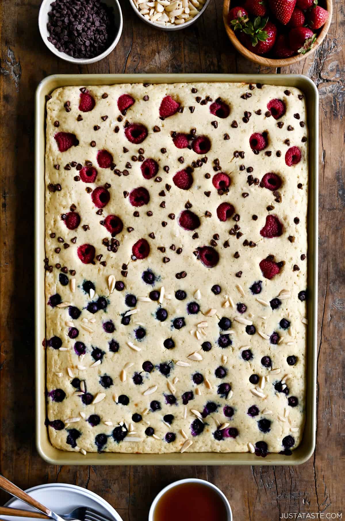 Sheet pan pancakes with blueberries on one half and raspberries and mini chocolate chips on the other half.