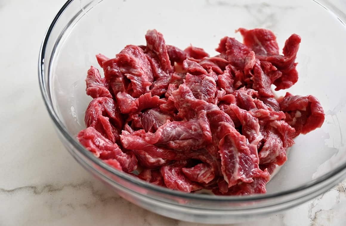 Raw slices of beef in a cornstarch slurry mixture