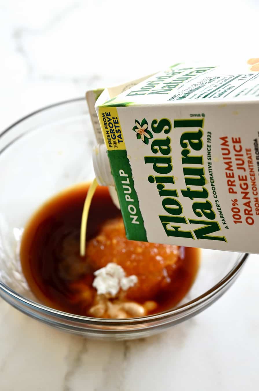 A carton of Florida's Natural Orange Juice being poured into a glass bowl