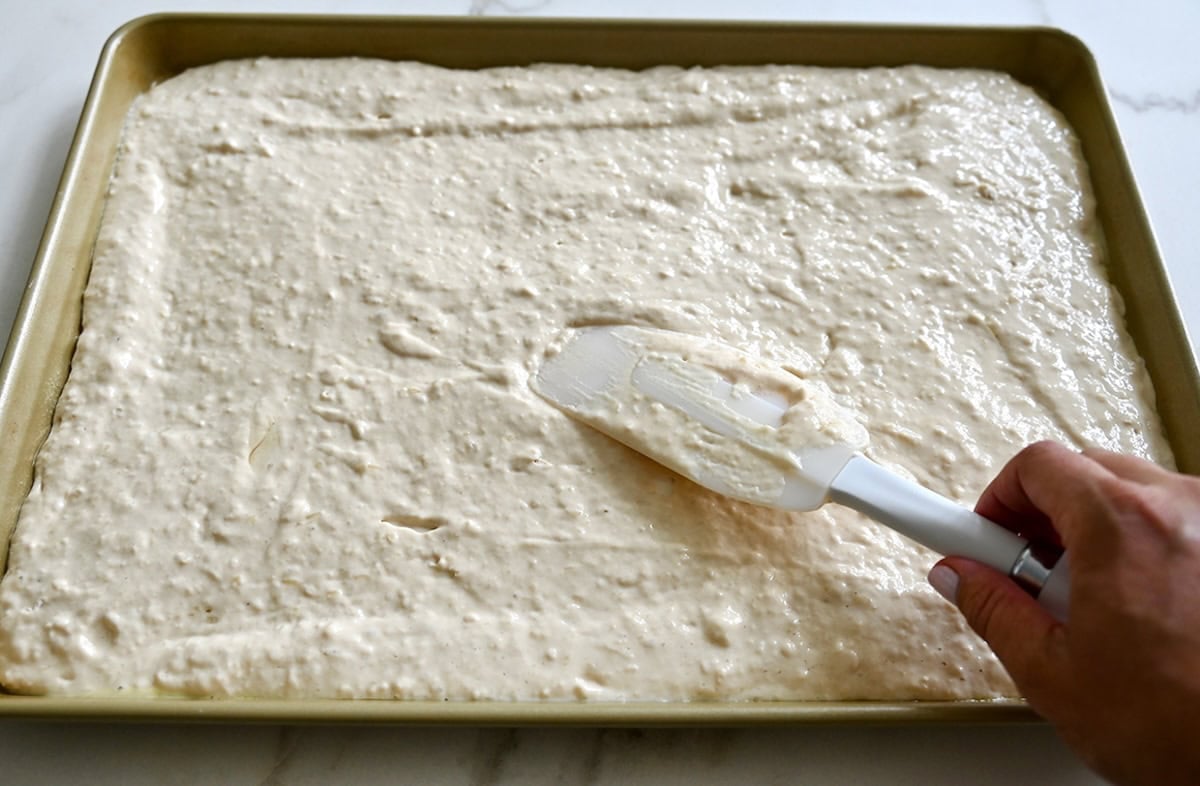 Spreading pancake batter into an even layer on a 9x13-inch baking sheet.