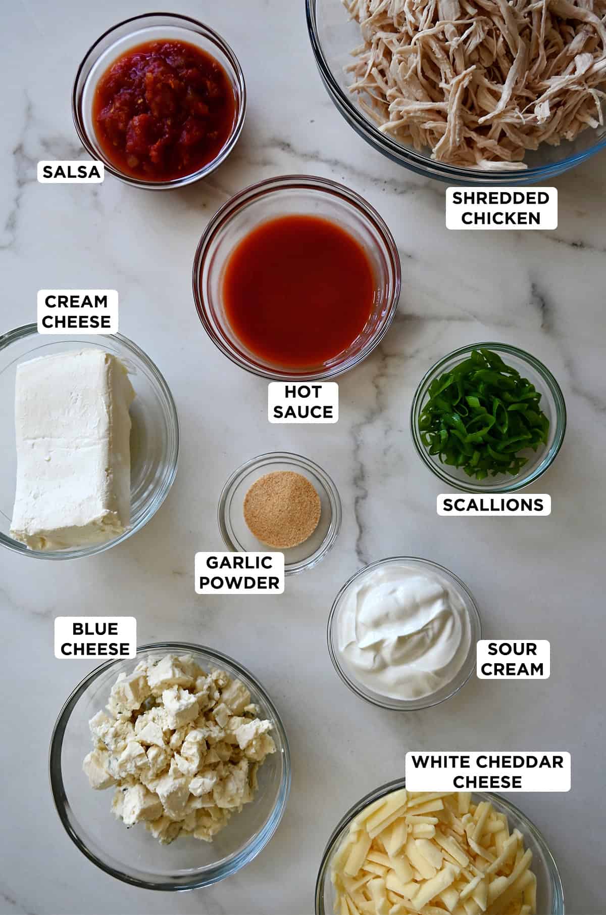 Ingredients to make buffalo chicken dip in glass bowls.