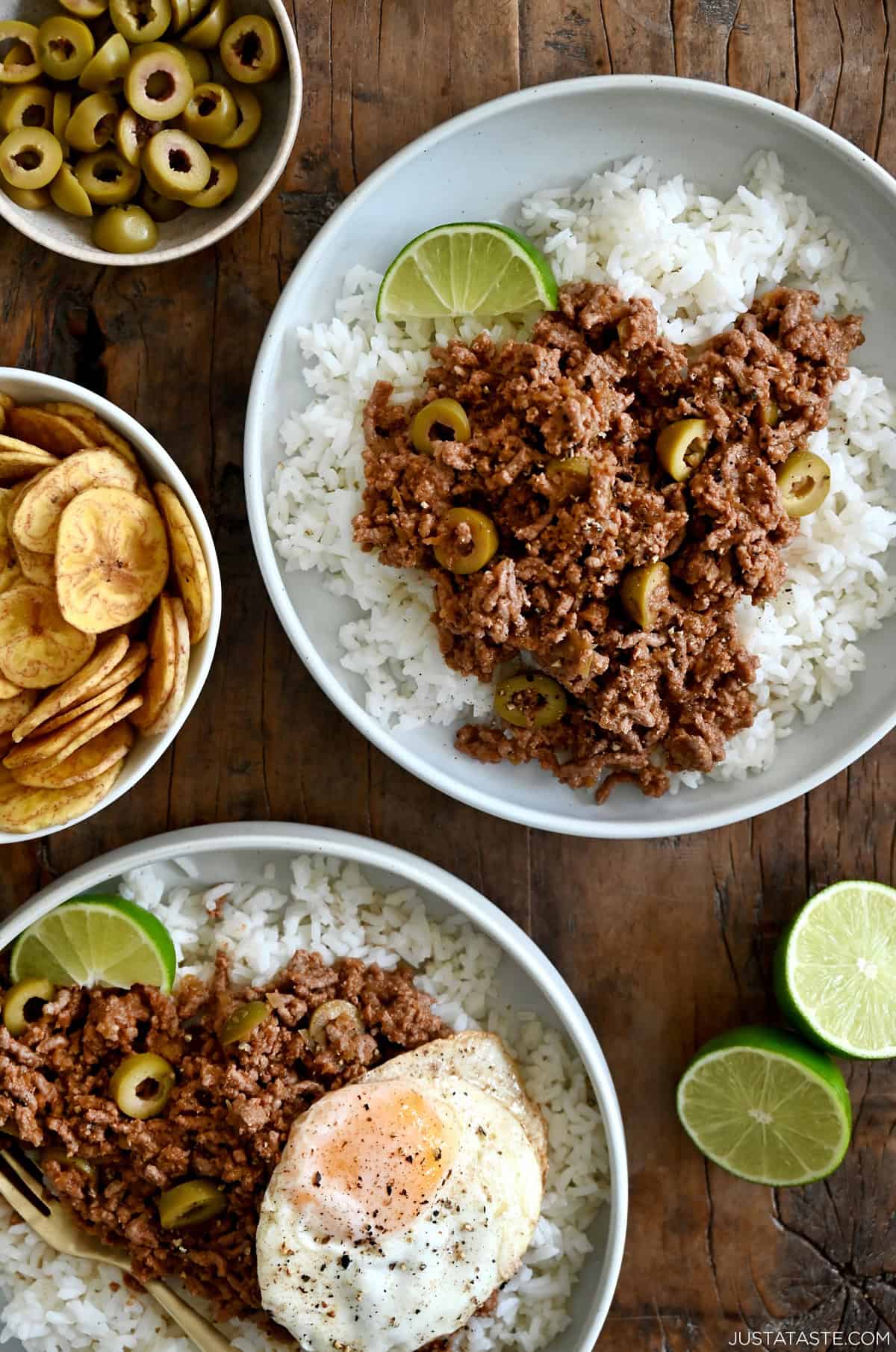 Two plates containing white rice topped with Cuban Picadillo and a fried egg.