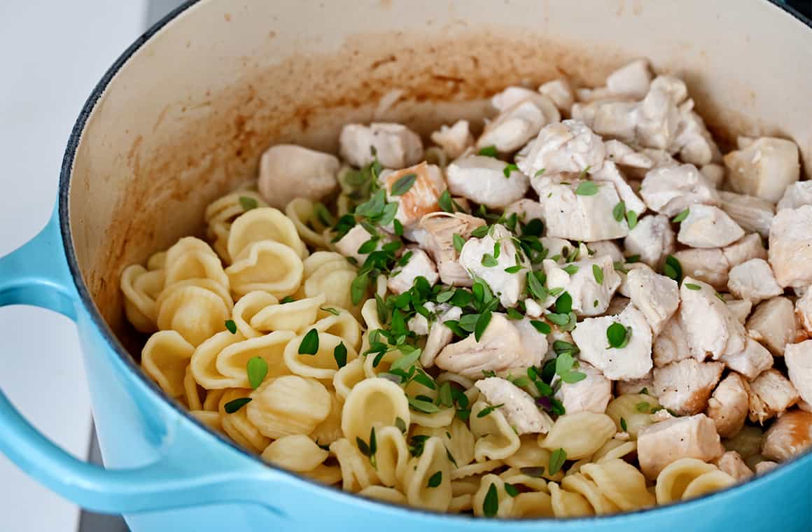 Orecchiette, cubed chicken breasts and fresh herbs in a large heavy-bottomed stockpot