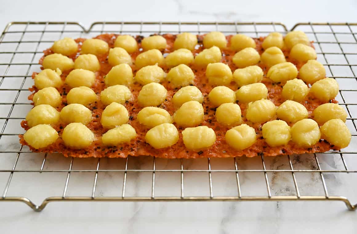 Gnocchi with a crispy parmesan bottom cooling on a wire rack.