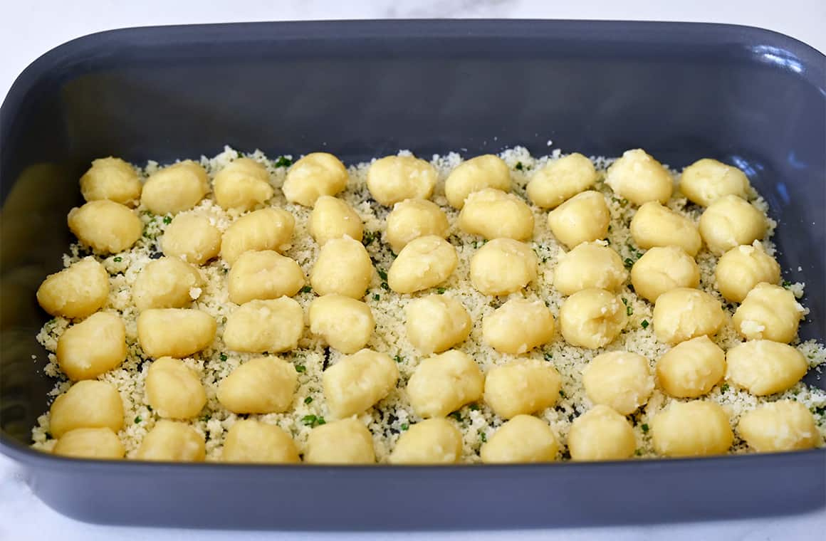 Gnocchi atop parmesan cheese in a baking dish.