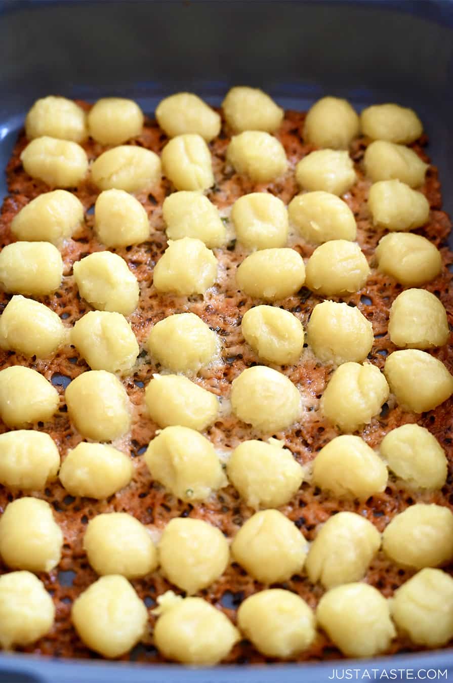 A close-up view of baked potato dumplings atop crispy cheese.