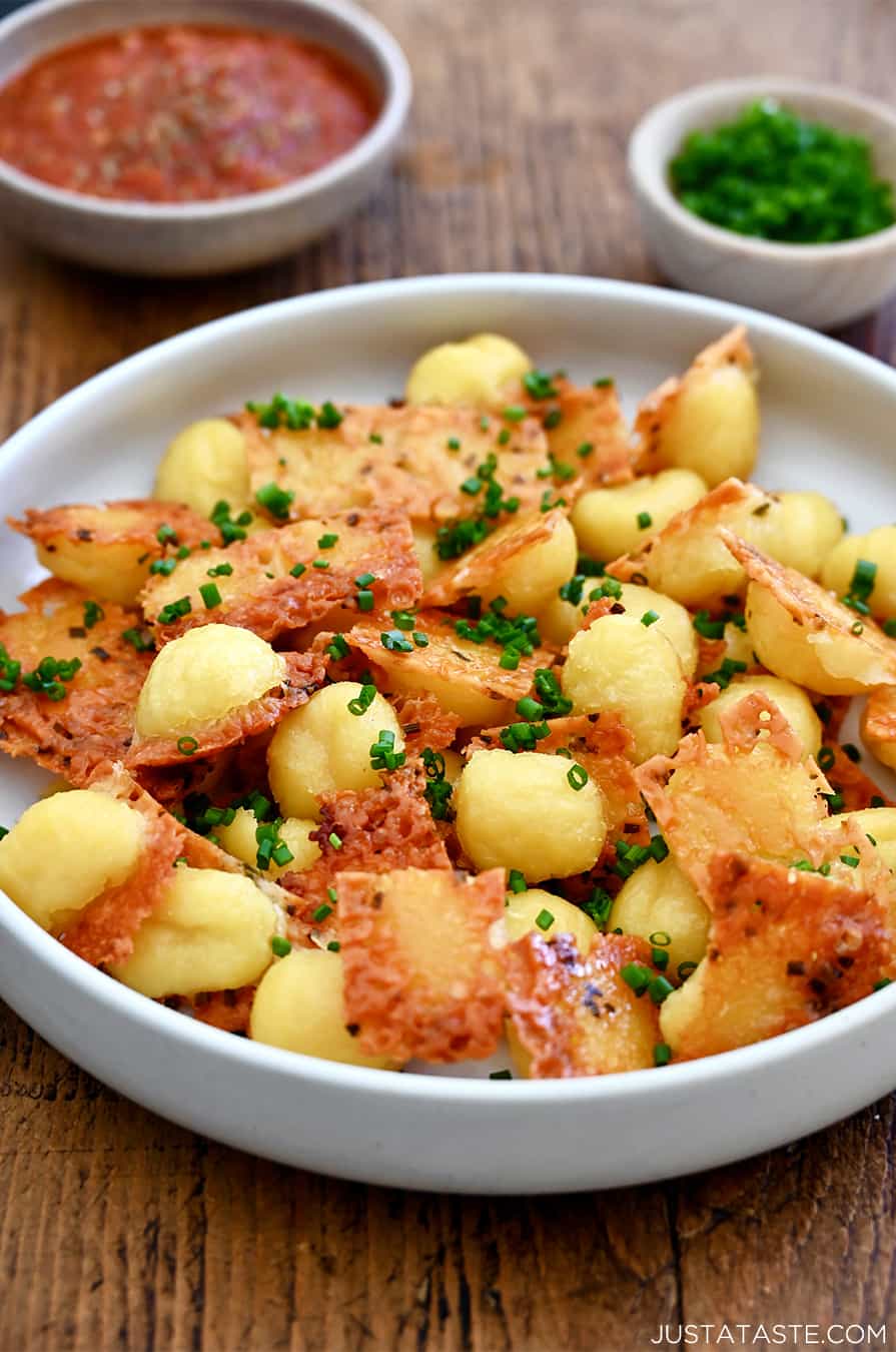 Crispy parmesan gnocchi garnished with chopped fresh chives piled high in a bowl.