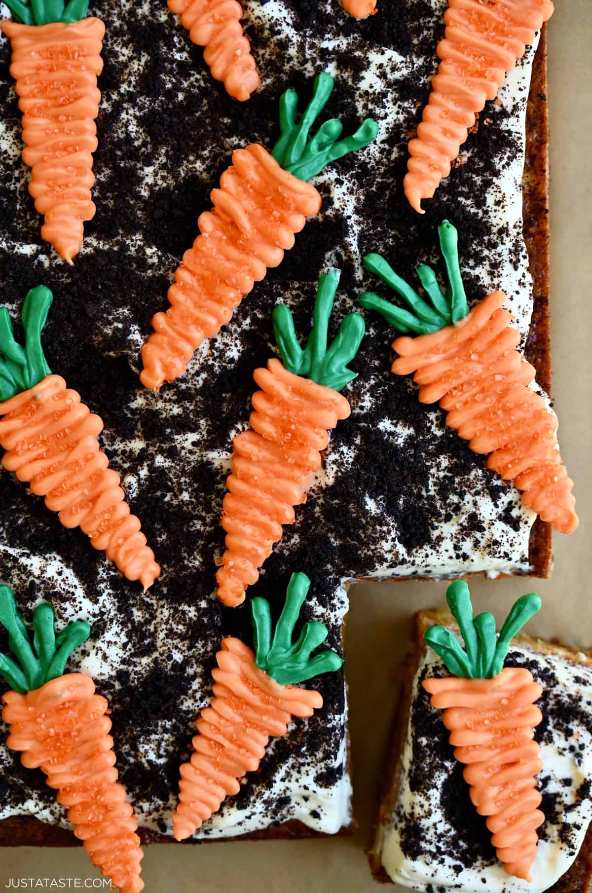 Easy carrot cake topped with frosting, crushed Oreos and candy melts in the shape of carrots.