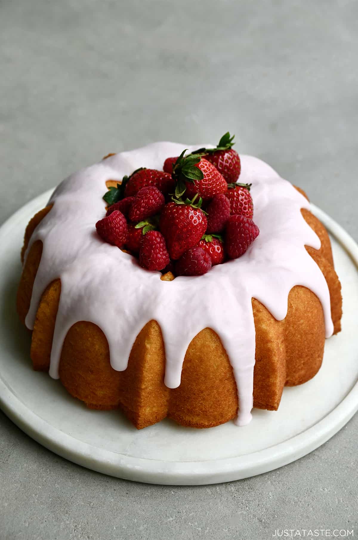 A lemon bundt cake with strawberry glaze and fresh strawberries in the center.