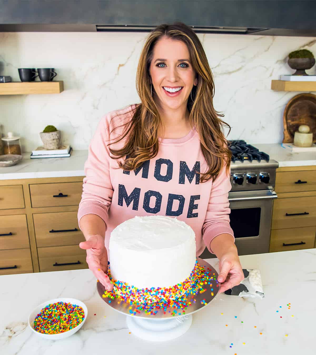 Kelly Senyei decorating a cake with rainbow sprinkles