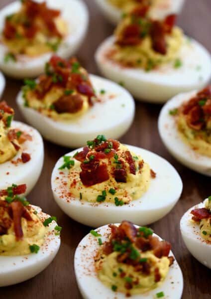 A close-up view of The Best Deviled Eggs with Bacon garnished with fresh chives and paprika.