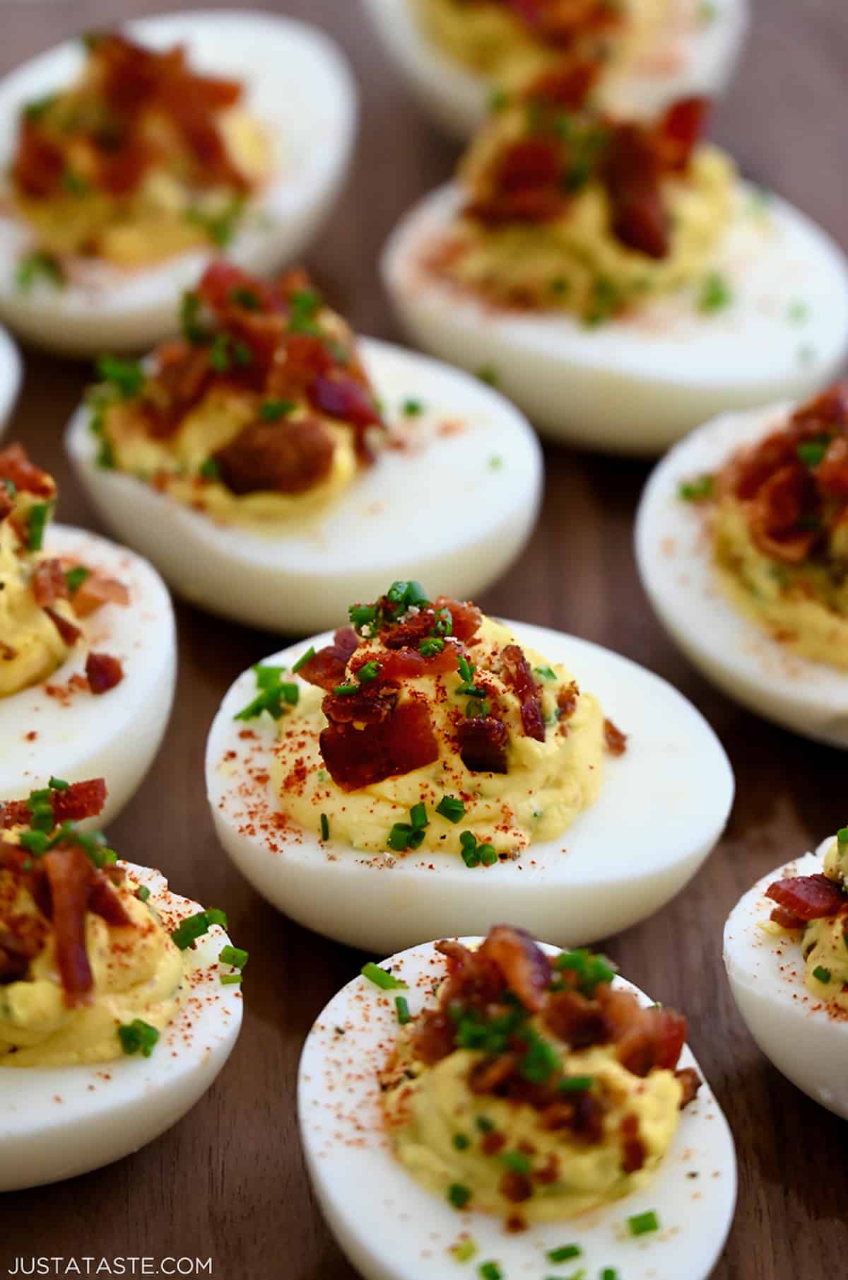 A close-up view of The Best Deviled Eggs with Bacon garnished with fresh chives and paprika.