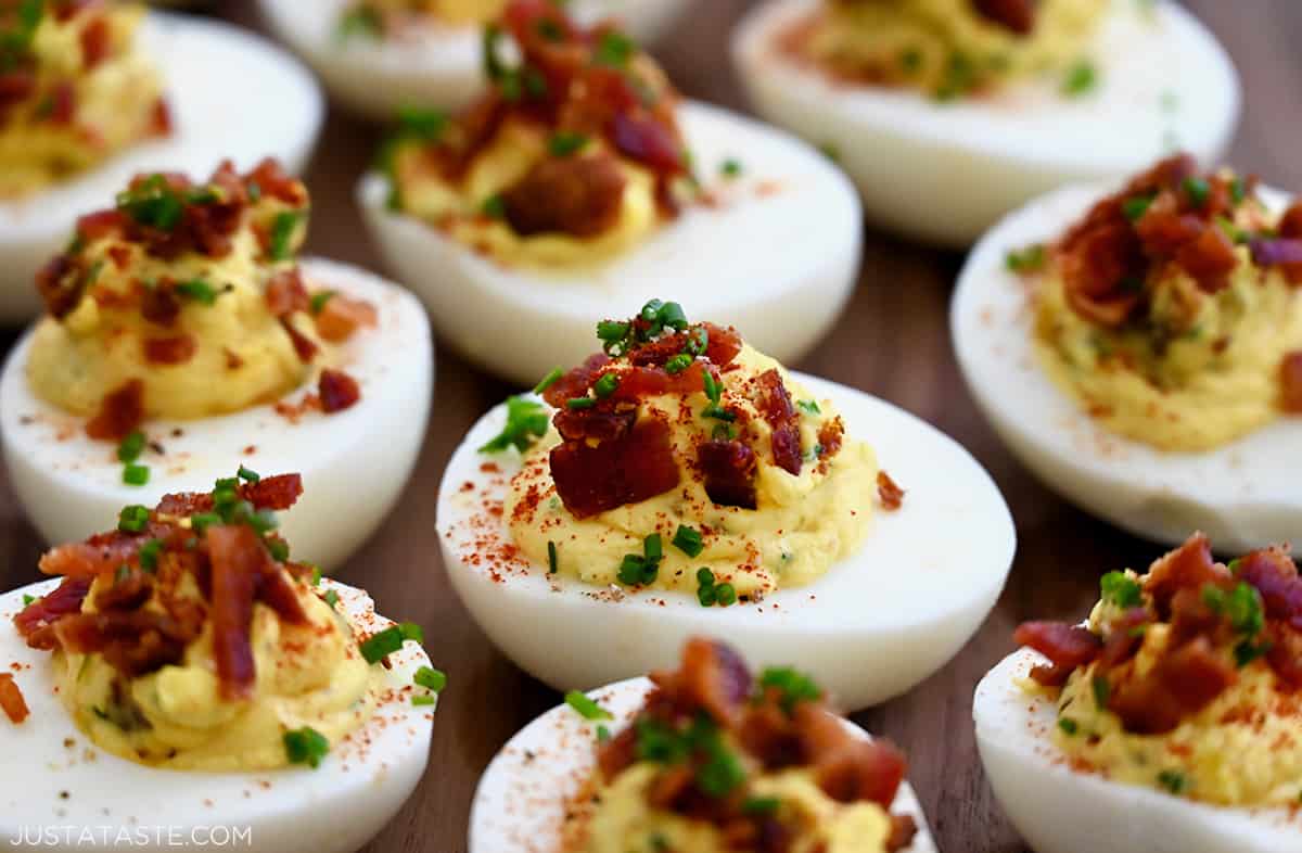 A close-up view of easy deviled eggs topped with crumbled bacon and chopped fresh chives.