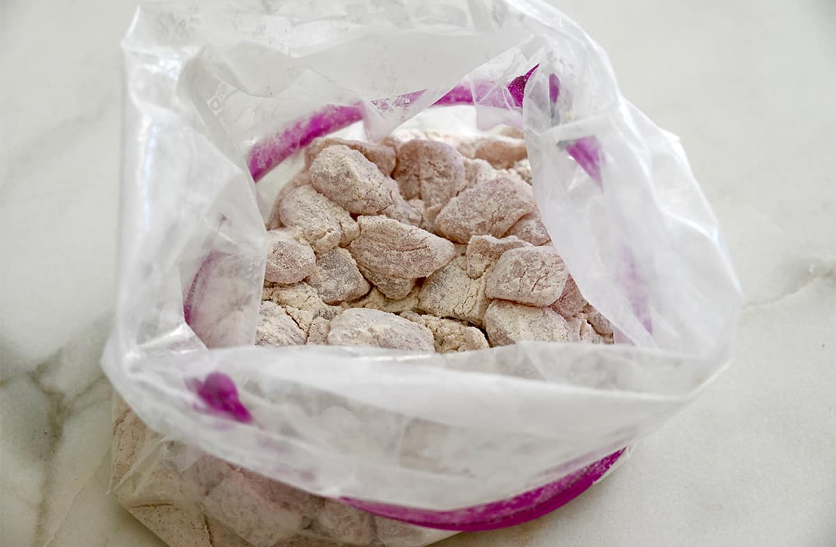 Pieces of chicken breasts covered with flour in a sealable plastic bag. 