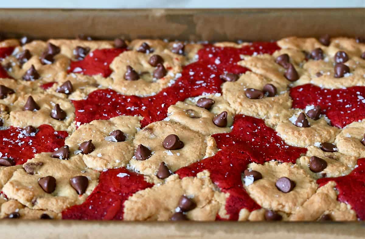 Baked red velvet brookies studded with chocolate chips in a baking pan.