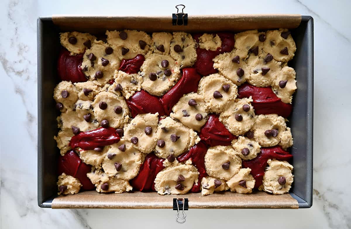 A top-down view of unbaked red velvet brownie cookies in a parchment paper-lined pan.