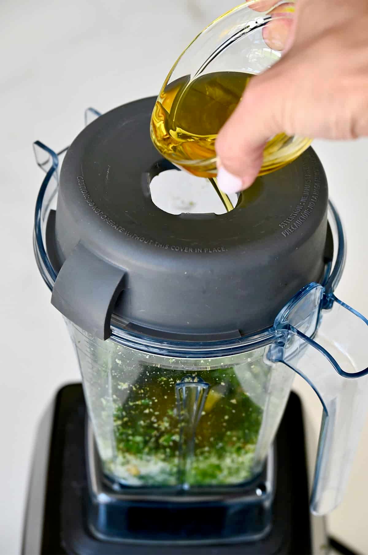 Streaming olive oil into a blender to make homemade pesto.
