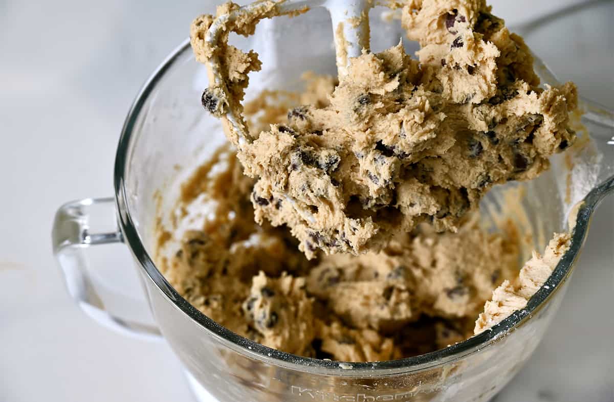 A stand mixer with the paddle attachment with chocolate chip cookie dough.