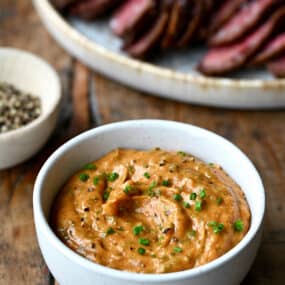 A small white bowl containing homemade cowboy butter garnished with chopped chives.