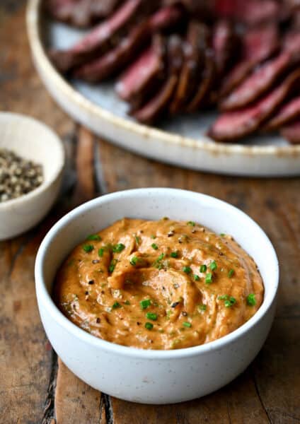 A small white bowl containing homemade cowboy butter garnished with chopped chives.