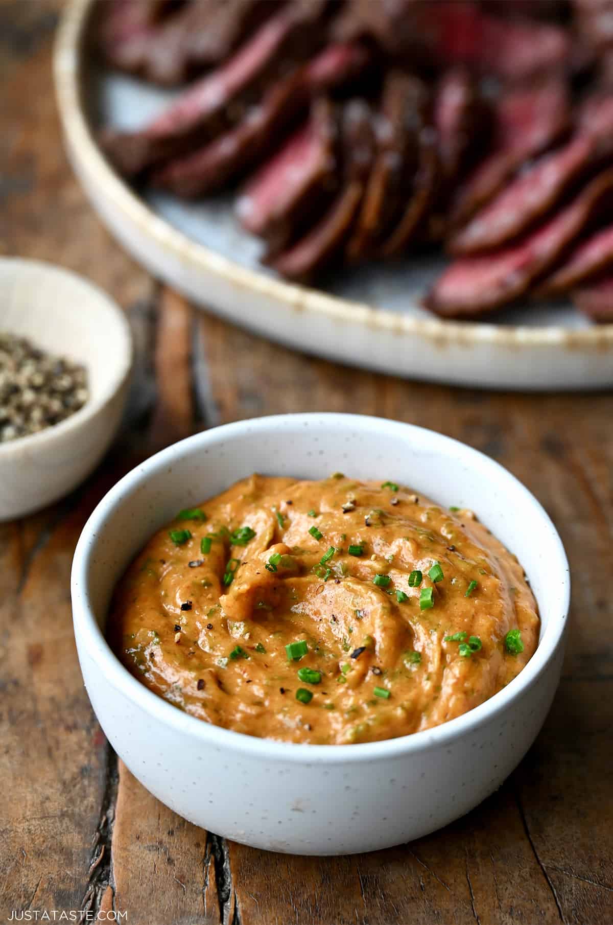 A small white bowl containing homemade cowboy butter garnished with chopped chives.