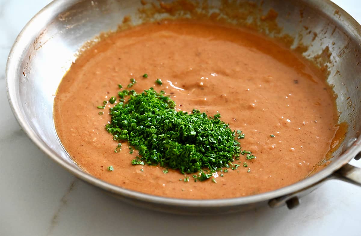 A saucepan containing cowboy butter with minced fresh green herbs.