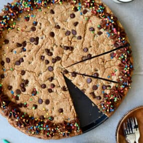 A top-down view of a Chocolate Chip Cookie Cake with chocolate frosting and rainbow sprinkles.