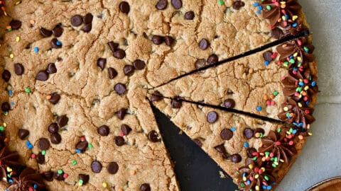 A top-down view of a Chocolate Chip Cookie Cake with chocolate frosting and rainbow sprinkles.