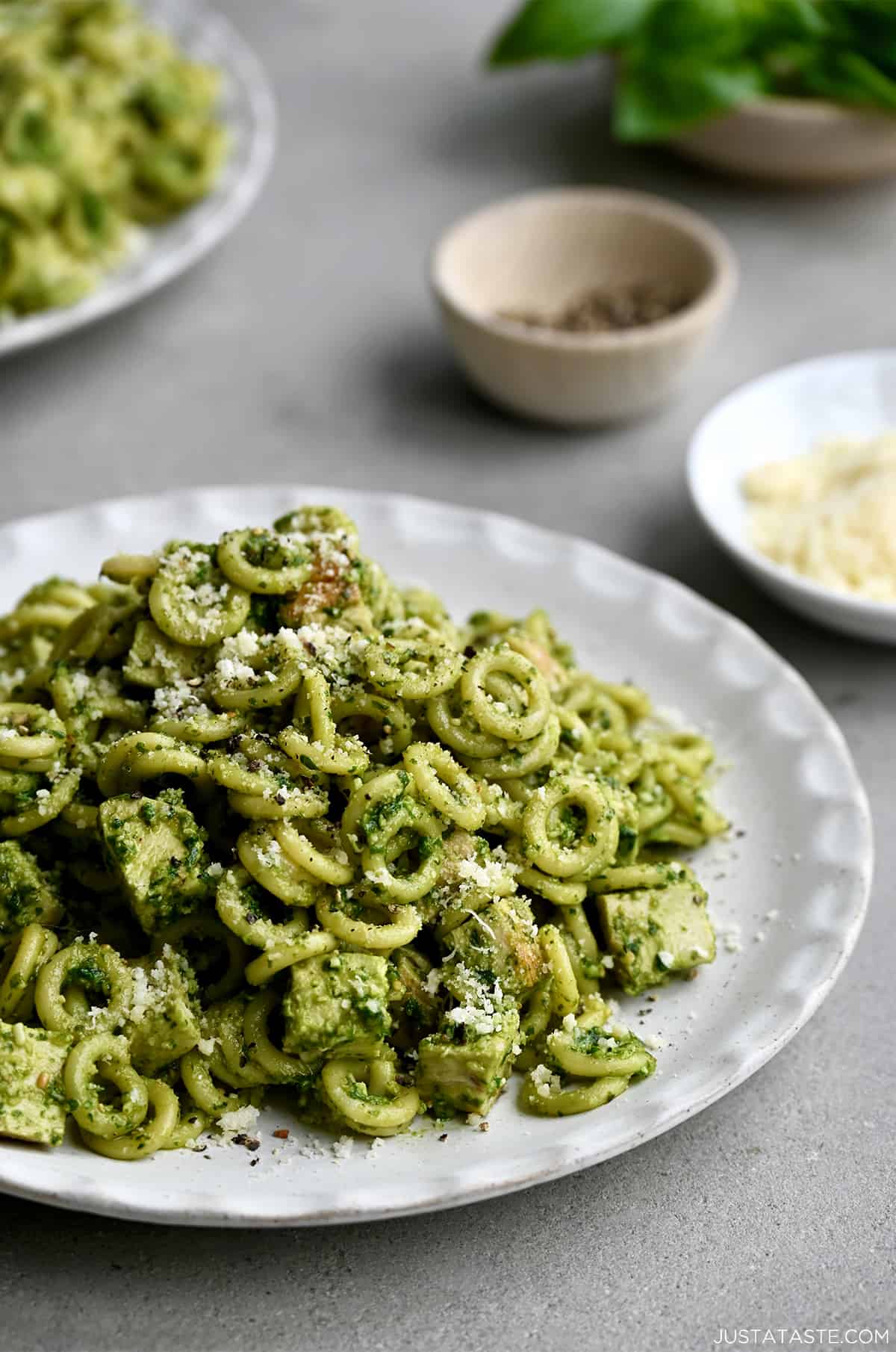 Easy pesto pasta with chicken pieces on a white dinner plate.