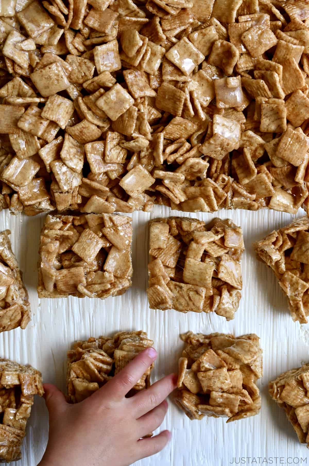 A child's hand reaches for a Cinnamon Toast Crunch bar.