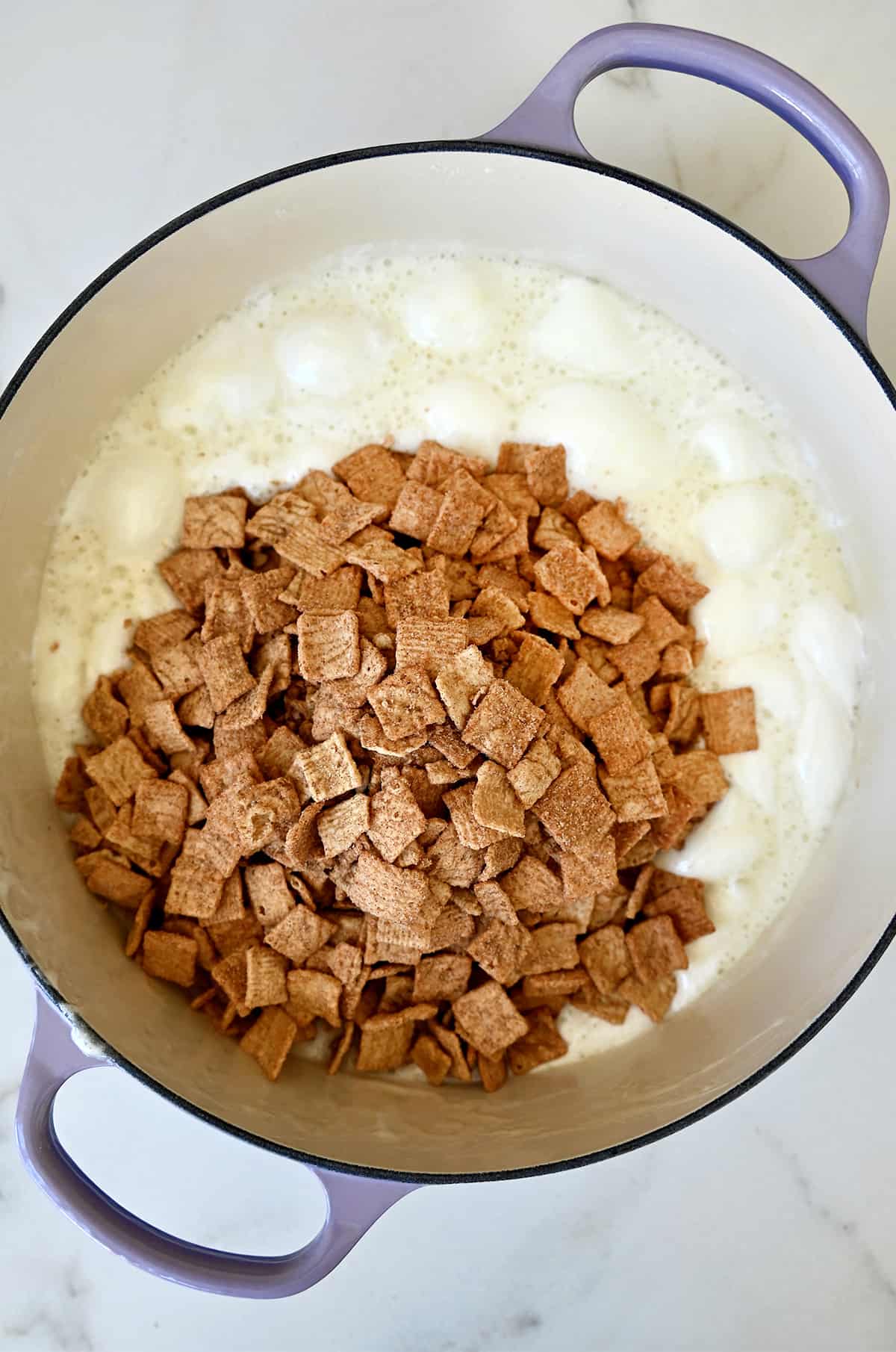 Cinnamon Toast Crunch cereal atop melted marshmallows in a large pot.