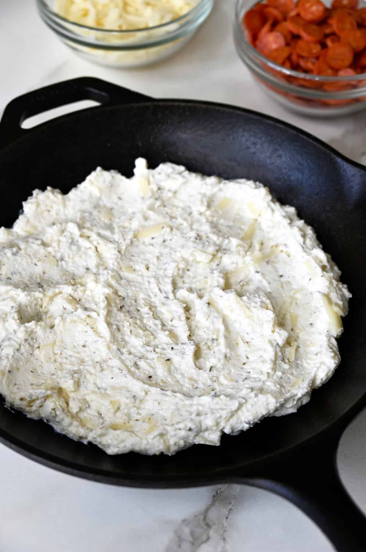 A cheese mixture spread on the bottom of a cast iron skillet.