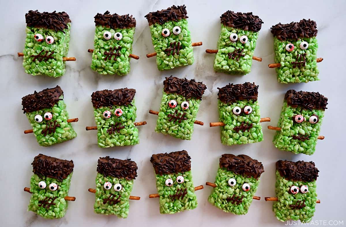Three rows of green Frankenstein Rice Krispie treats with chocolate-sprinkle hair, candy eyes and pretzel stick bolts.