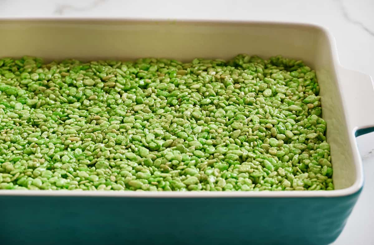 Green Rice Krispie treats in an even layer in a baking dish.