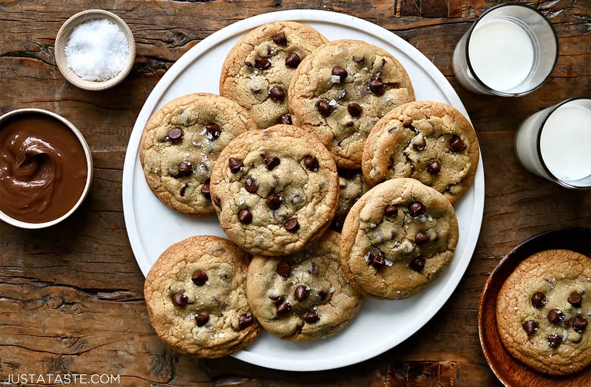 Nutella chocolate chip cookies on a round serving platter next to two glasses of milk.