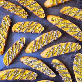 Pumpkin pie biscotti that are drizzled with melted chocolate and topped with chopped pumpkin seeds.