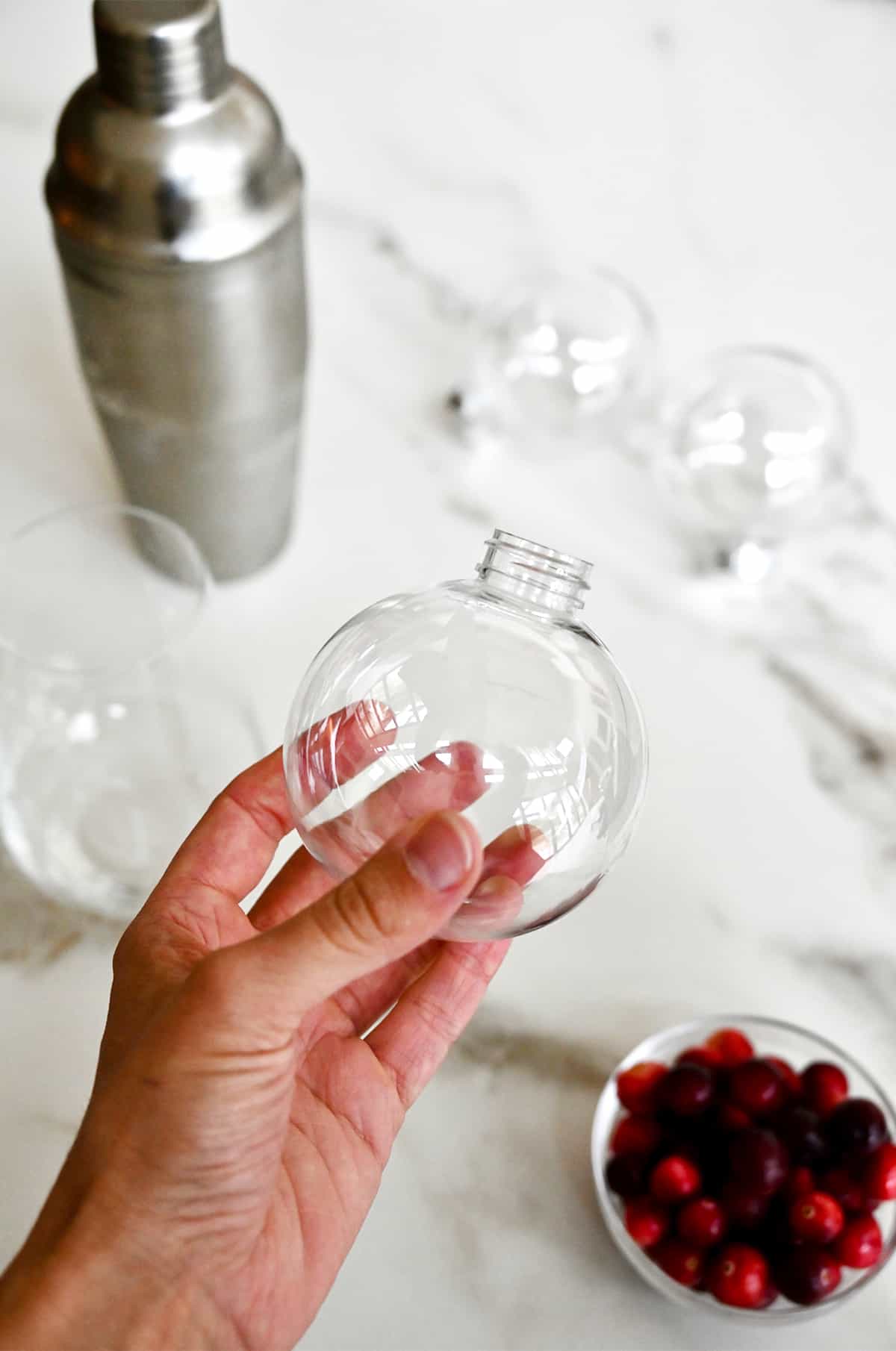 A hand holds a clear plastic Christmas ornament ball.