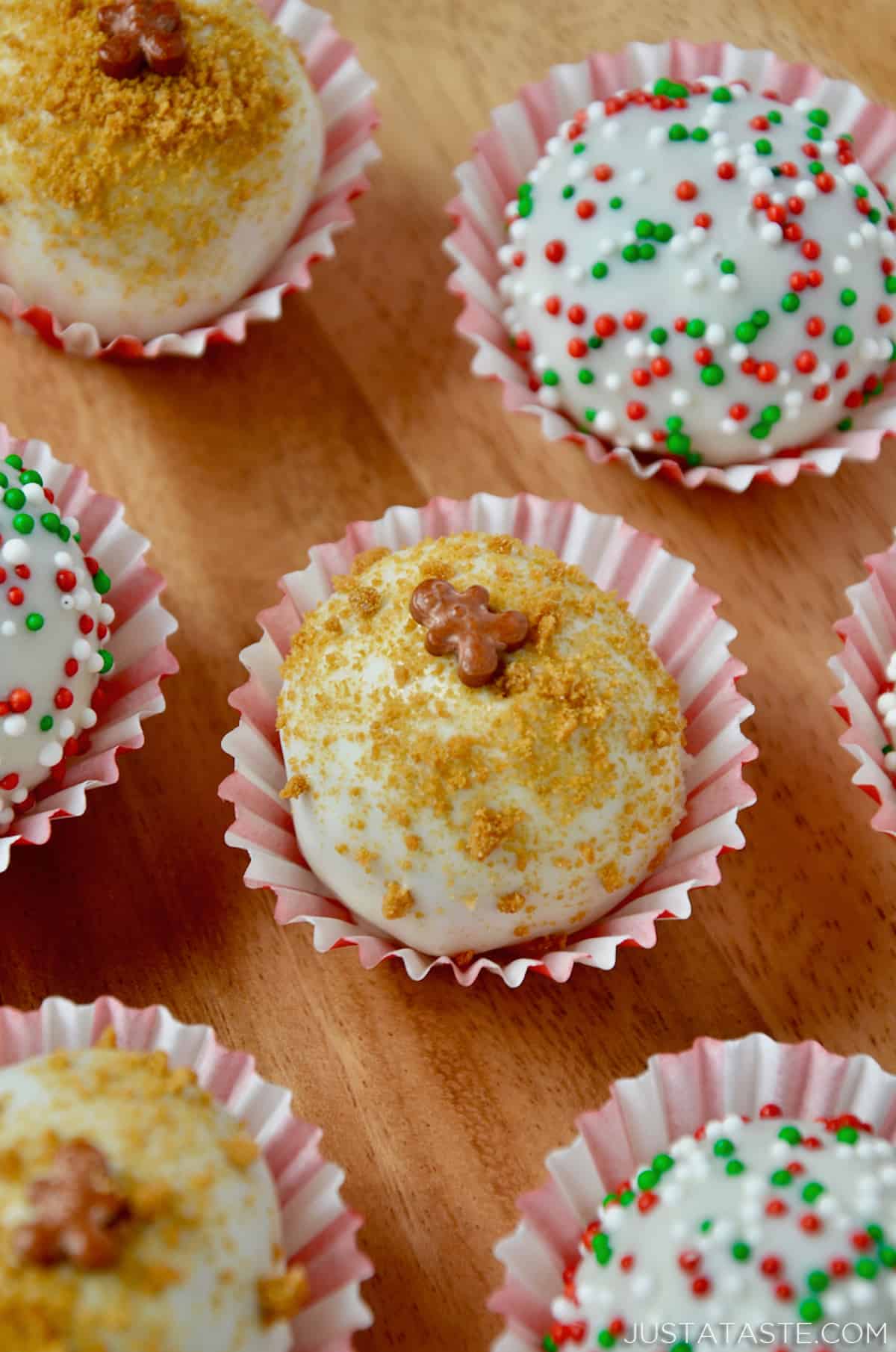 Seven chocolate- and sprinkle-covered gingerbread cookie balls in red and white striped wrappers.