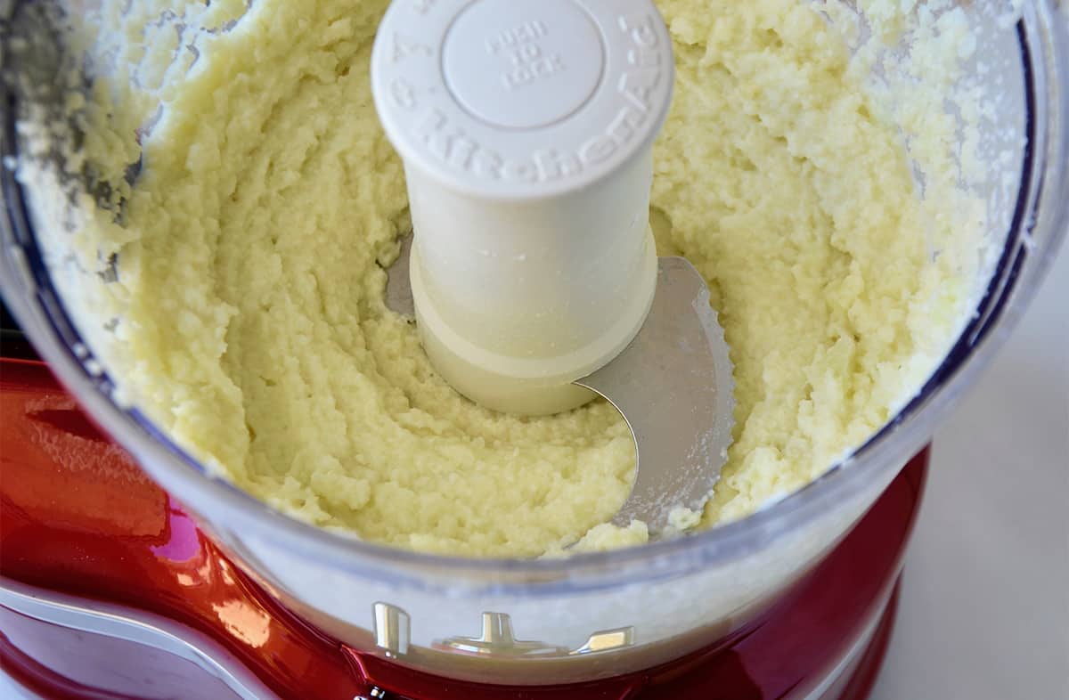 Pureed cauliflower in the bowl of a food processor.