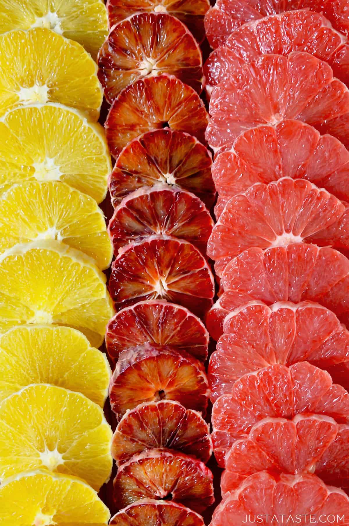 Three vertical rows of peeled, sliced oranges, blood oranges and grapefruits.