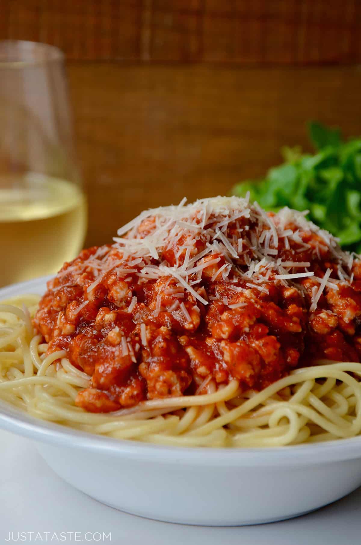 A bowl of spaghetti topped with turkey bolognese and grated cheese.