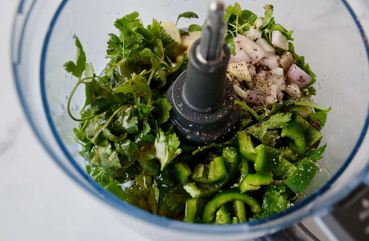 Cilantro, parsley, shallots, garlic, jalapeno, honey, lime juice, red wine vinegar, salt and pepper in the bowl of a food processor.