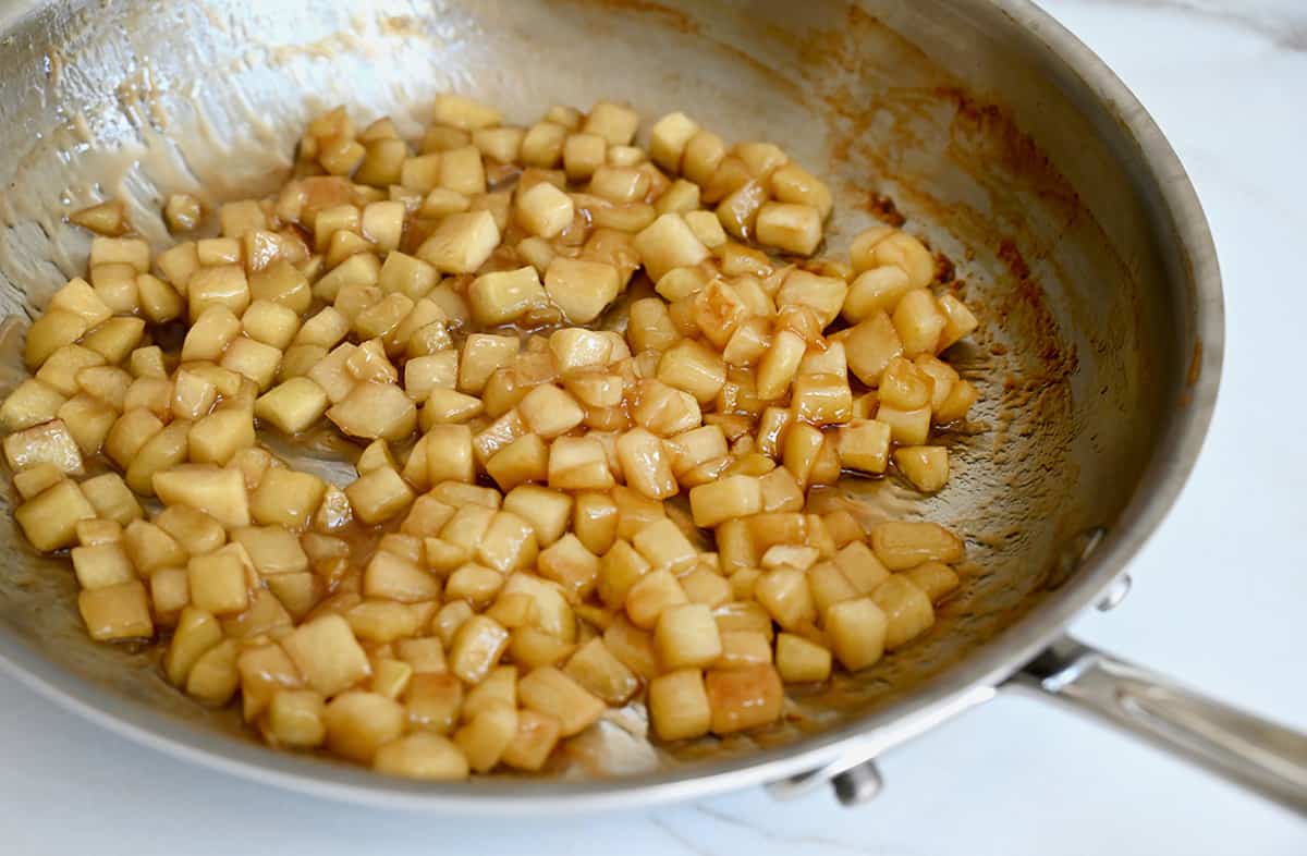 Sautéed apples with caramel sauce in a stainless steel skillet.