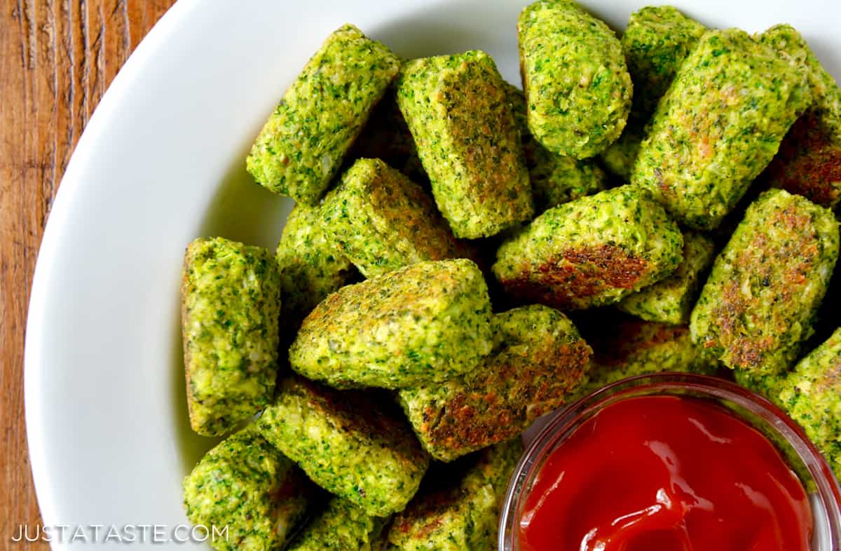 A platter of baked broccoli tots and a small bowl of ketchup.